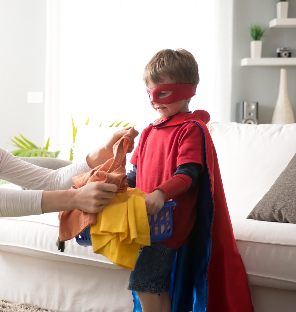 Boy with superpower cape helping with laundry