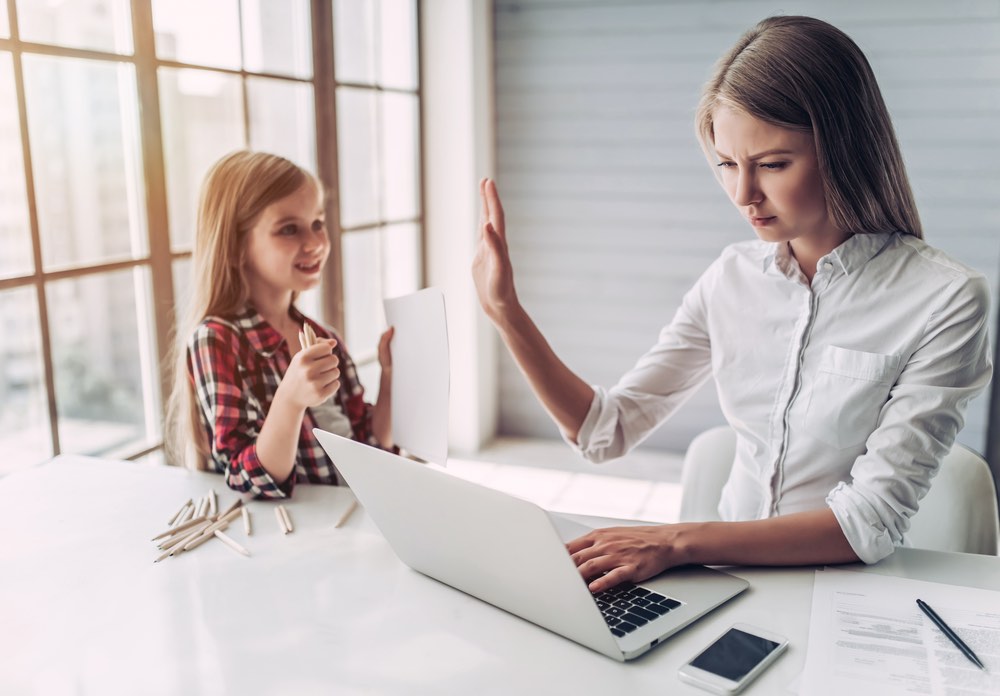 Working Mother Holding Hand Up for Daughter Not to Bother Her