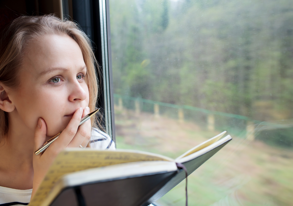 Woman writing journal on train